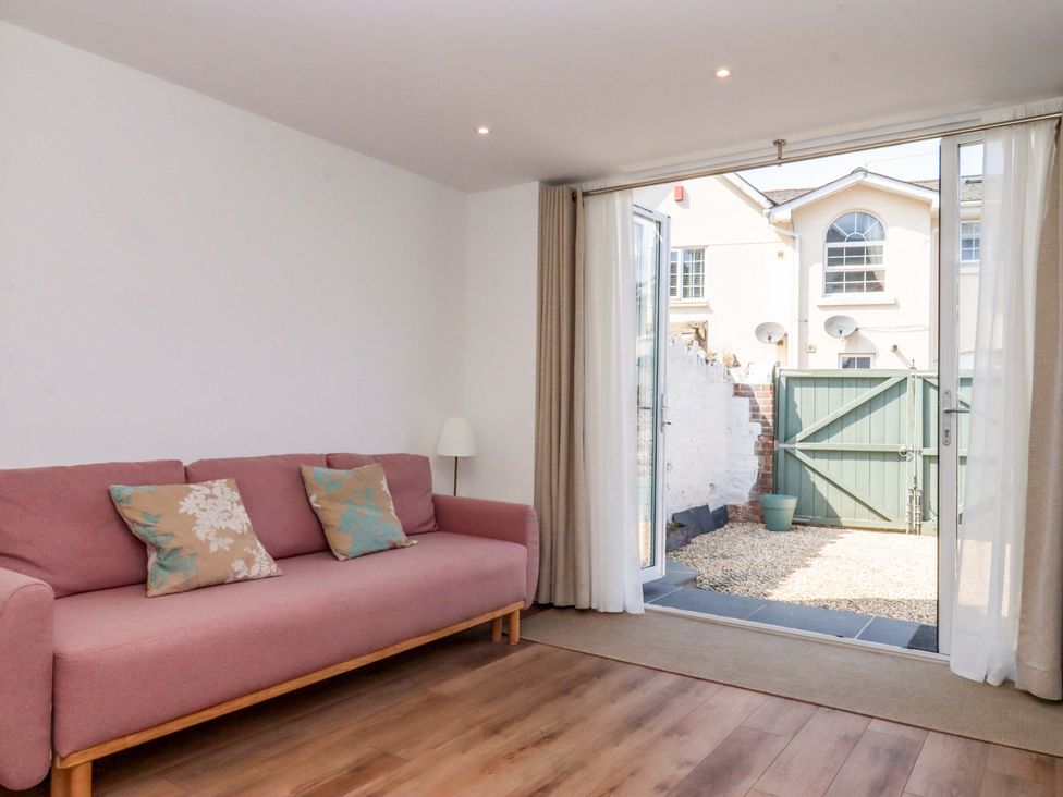 A living room with a sofa and access to a garden at Kents Cottage in Torquay