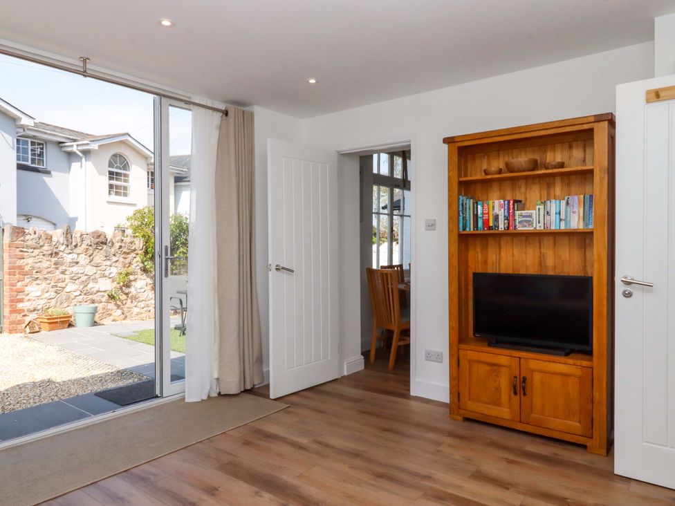 A living room with a bookshelf and a television at Kents Cottage in Torquay