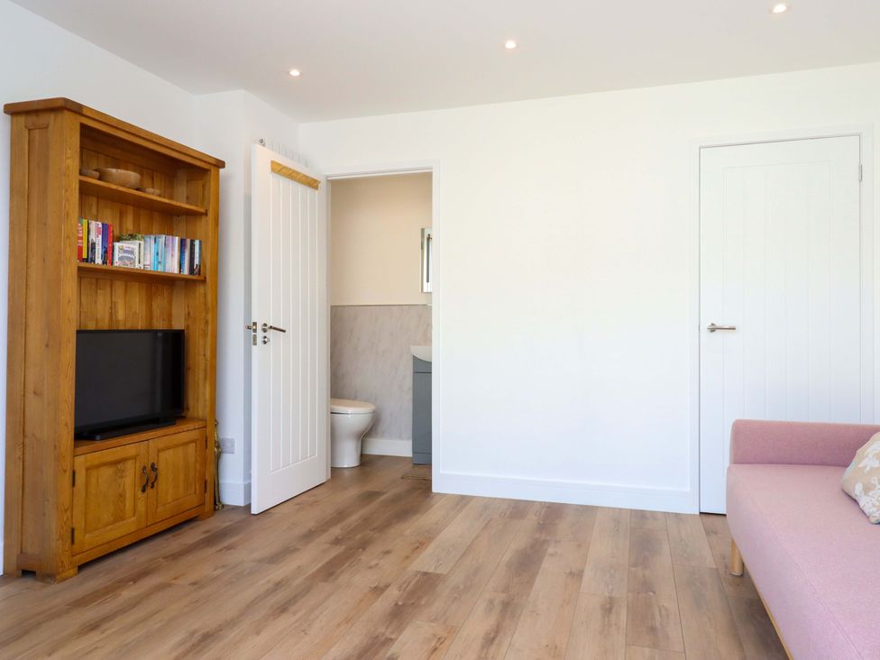 A bathroom with a tv and bookshelf at Kents Cottage in Torquay
