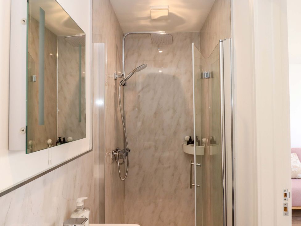 A bathroom with a shower and mirror at Kents Cottage in Torquay