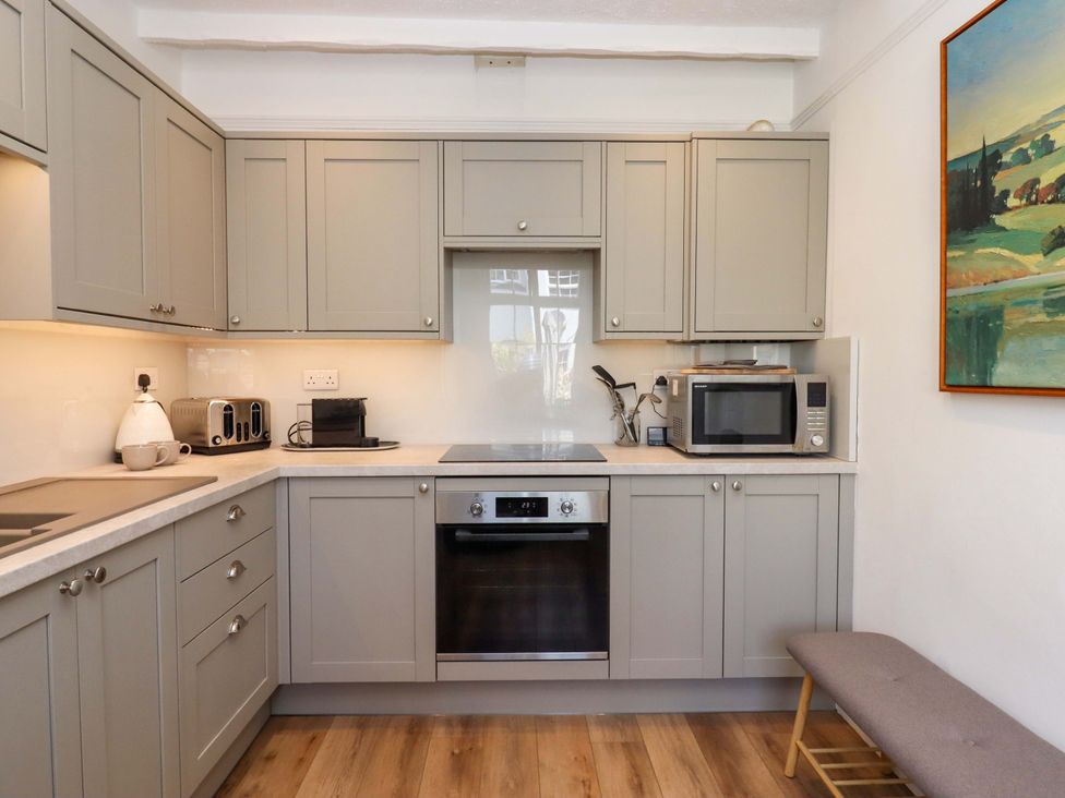 A kitchen with cabinets and appliances at Kents Cottage in Torquay