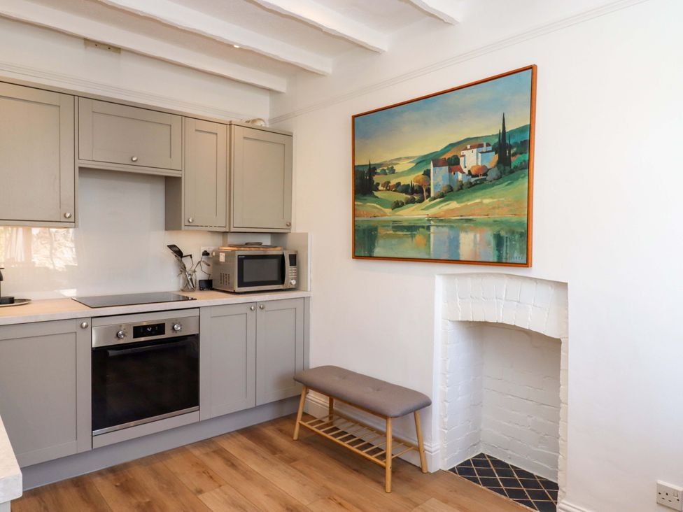 A kitchen with gray cabinets and a painting at Kents Cottage in Torquay