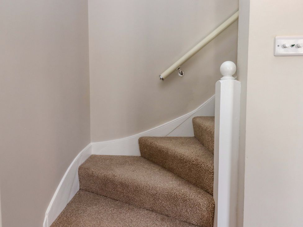 A staircase with carpet and a handrail at Kents Cottage in Torquay