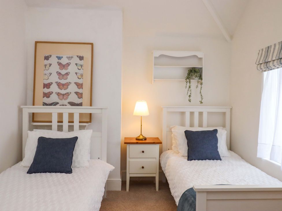 A bedroom with twin beds and a lamp on a nightstand at Kents Cottage in Torquay