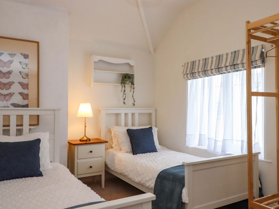 A bedroom with two beds and a lamp at Kents Cottage Torquay