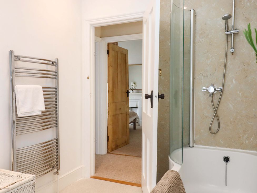 A bathroom with a towel radiator and bathtub at Kents Cottage in Torquay