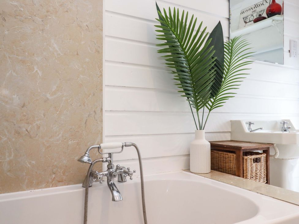 A bathroom with a bath tub and sink at Kents Cottage in Torquay