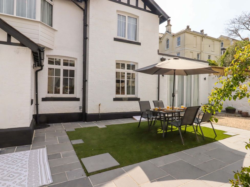 A garden with a dining table and chairs under an umbrella at Kents Cottage in Torquay