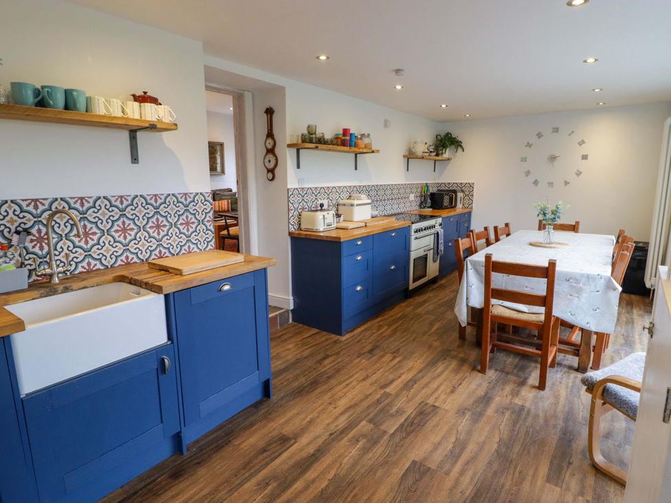 A kitchen with a large sink, cabinets, and a dining table at No.8 Millmoor Farm Cottage in Broad Haven
