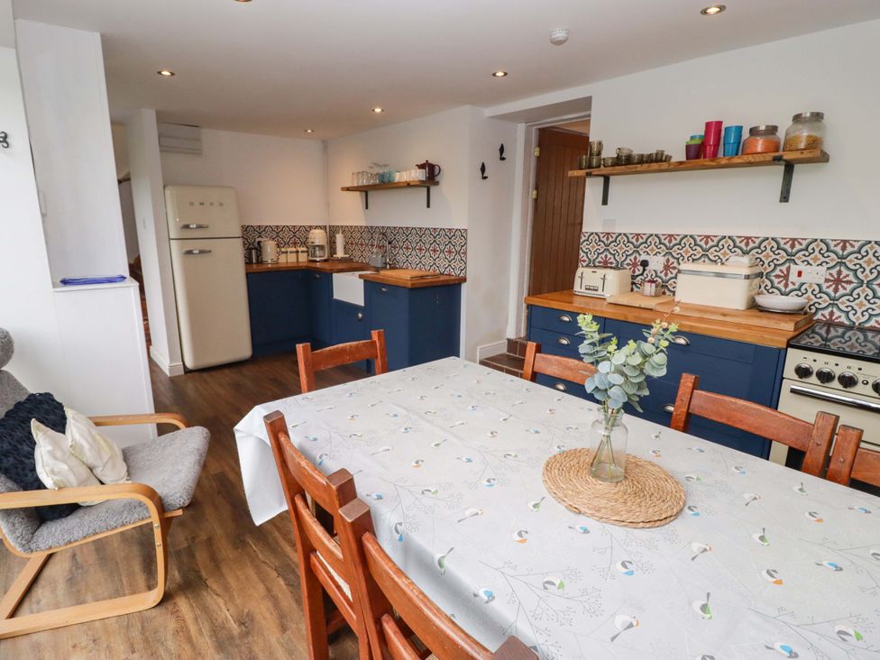A kitchen with a dining table and refrigerator at No.8 Millmoor Farm Cottage in Broad Haven
