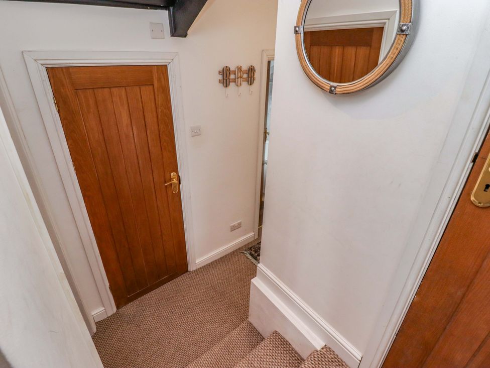 A hallway with a door and mirror at No.8 Millmoor Farm Cottage in Broad Haven