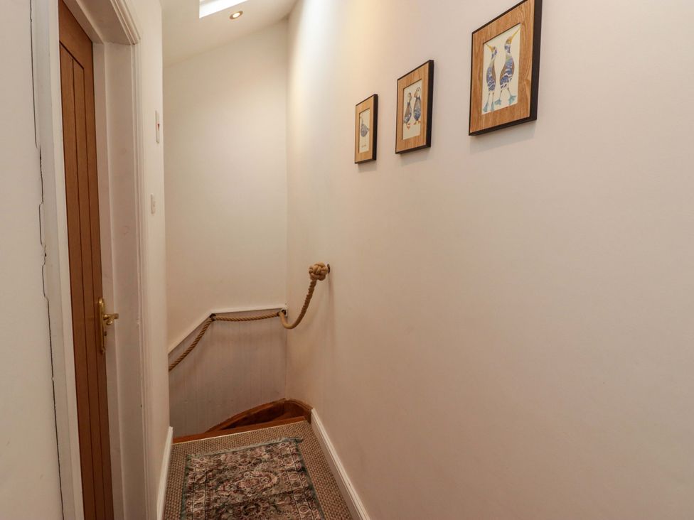 A hallway with a staircase and framed art at No.8 Millmoor Farm Cottage in Broad Haven