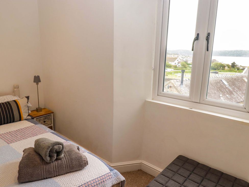A bedroom with a bed, lamp and window view at No.8 Millmoor Farm Cottage in Broad Haven