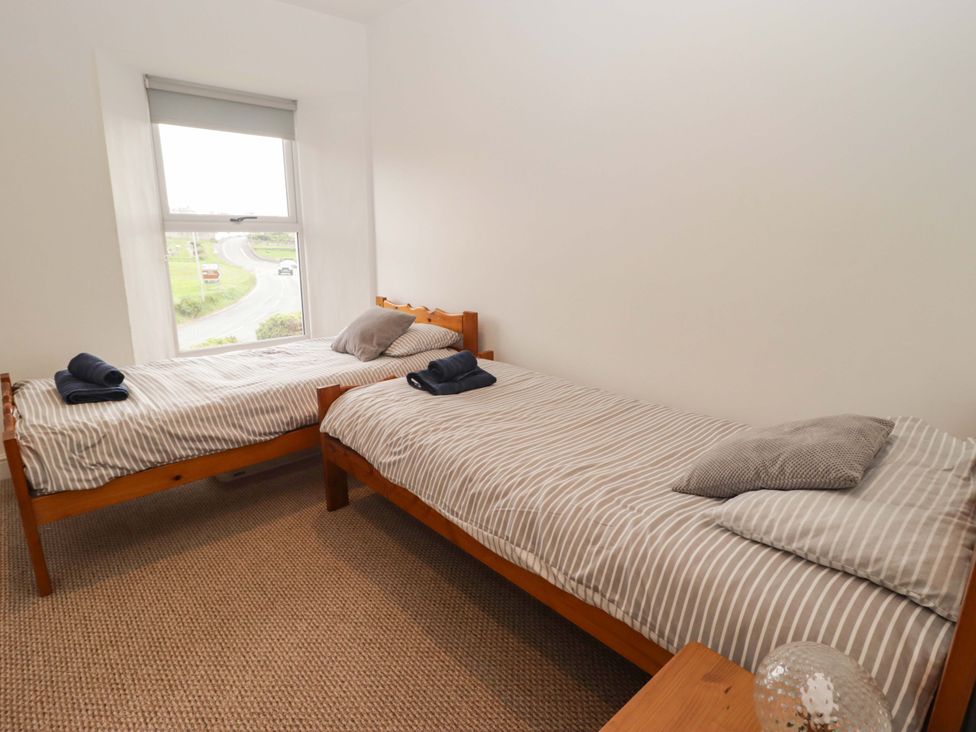 A bedroom with two single beds and a window at No.8 Millmoor Farm Cottage, Broad Haven