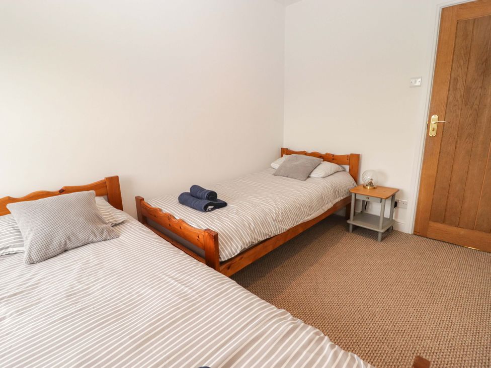 A bedroom with two beds and a side table at No.8 Millmoor Farm Cottage in Broad Haven