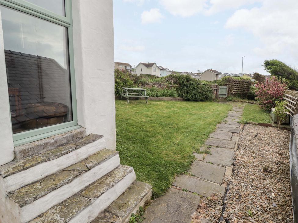 A garden with a bench and stone pathway at No.8 Millmoor Farm Cottage Broad Haven