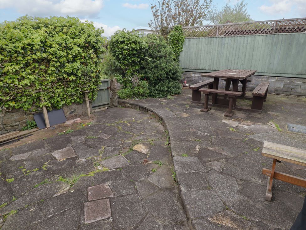 A garden with patio stones and a wooden table with benches at No.8 Millmoor Farm Cottage in Broad Haven