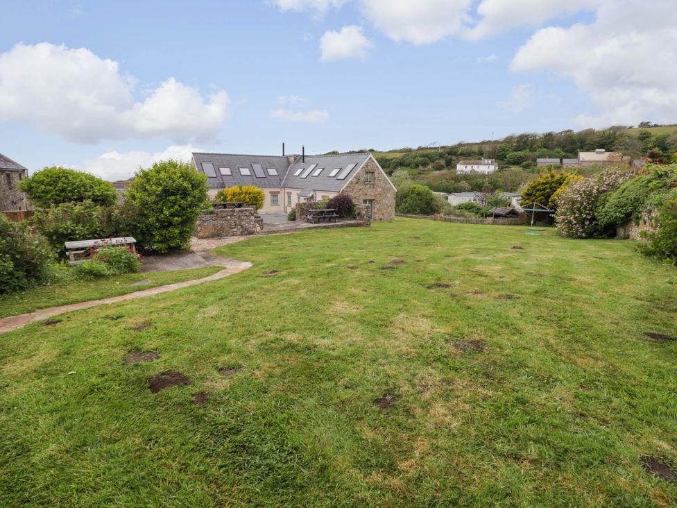 A garden with grass and a stone building at No.8 Millmoor Farm Cottage in Broad Haven