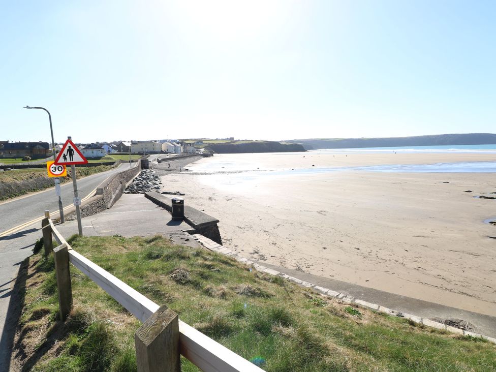 A beach view with road, sign, and houses at No.8 Millmoor Farm Cottage in Broad Haven