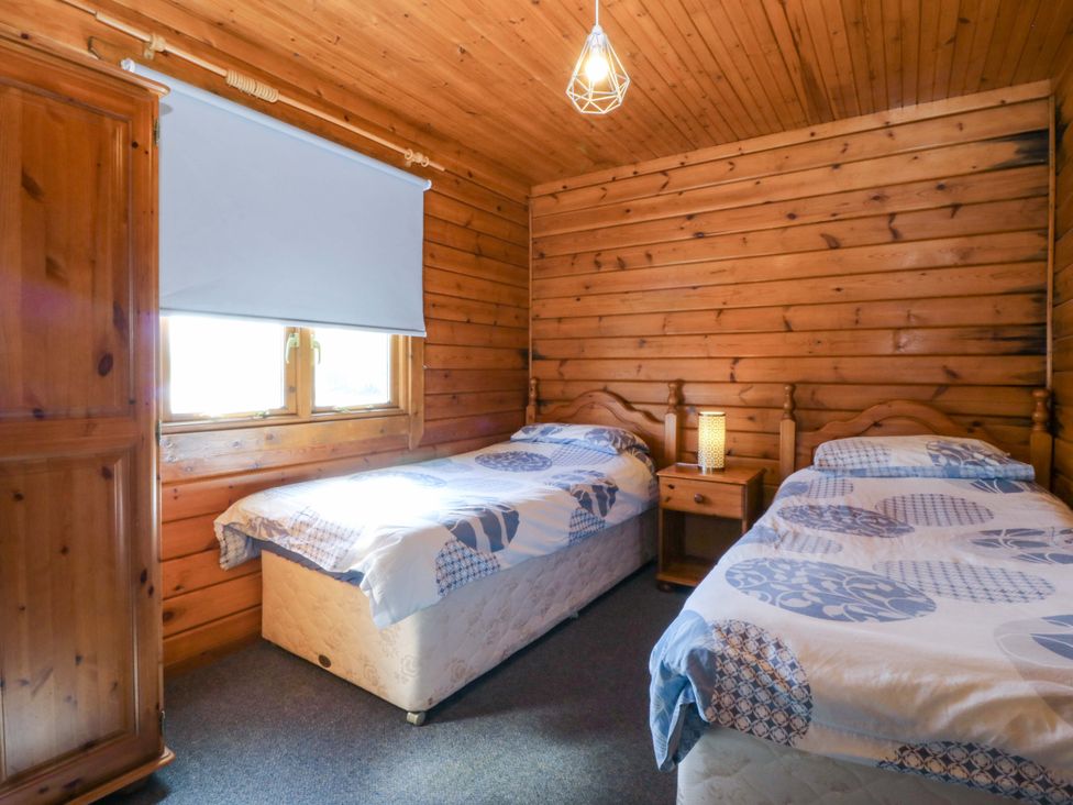 A bedroom with two beds and a wardrobe at Lodge 1 - Bron Eifion, Criccieth