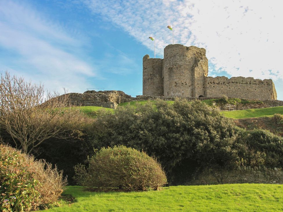 A castle with flags on top and greenery surrounding it at Criccieth