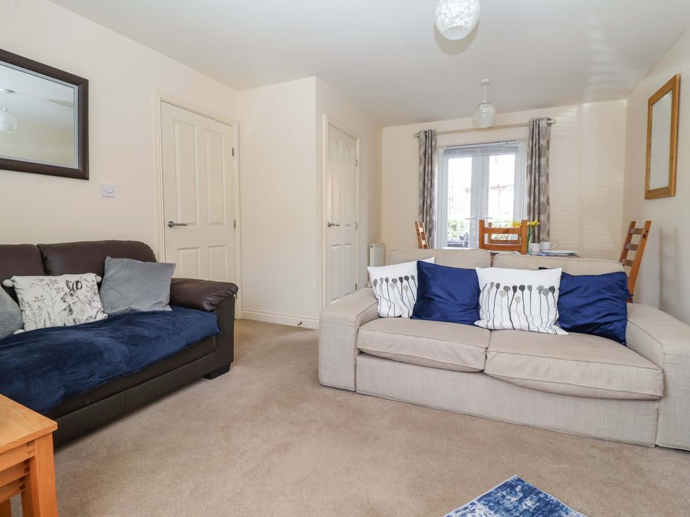 A living room with sofa and dining area at 4 Perran Court in Filey