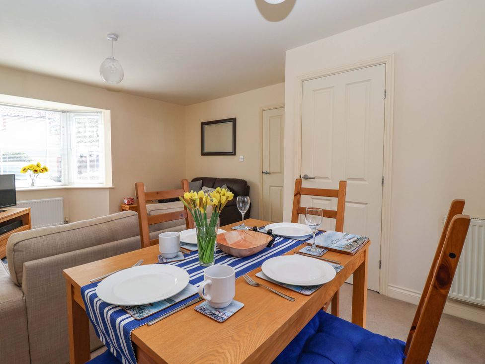 A dining room with a table set for meals at 4 Perran Court in Filey