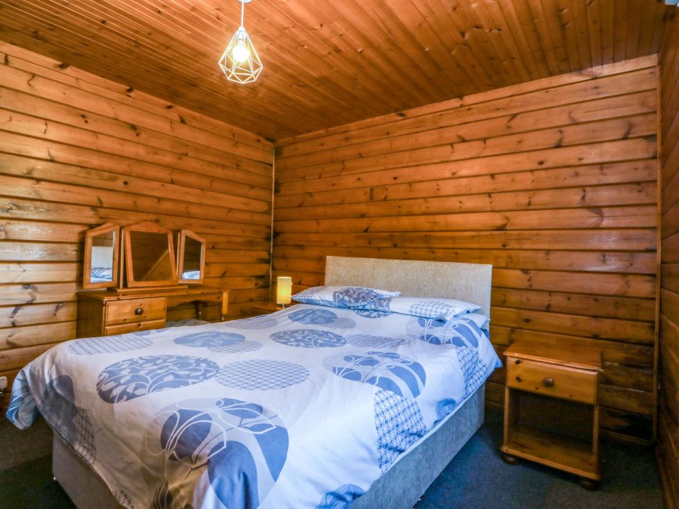 A bedroom with a bed and a dresser at Lodge 2 - Bron Eifion