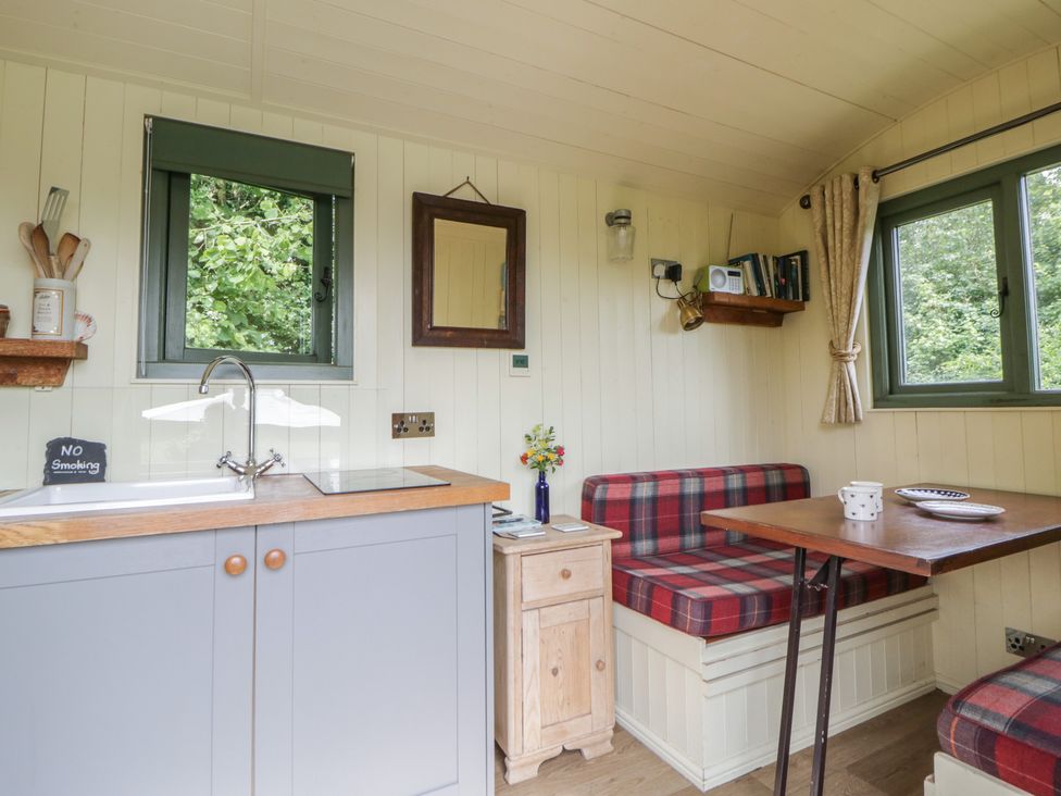 A kitchen with a dining table and seating at The Three Spaniels Shepherds Hut Cwrtnewydd near Llanybydder