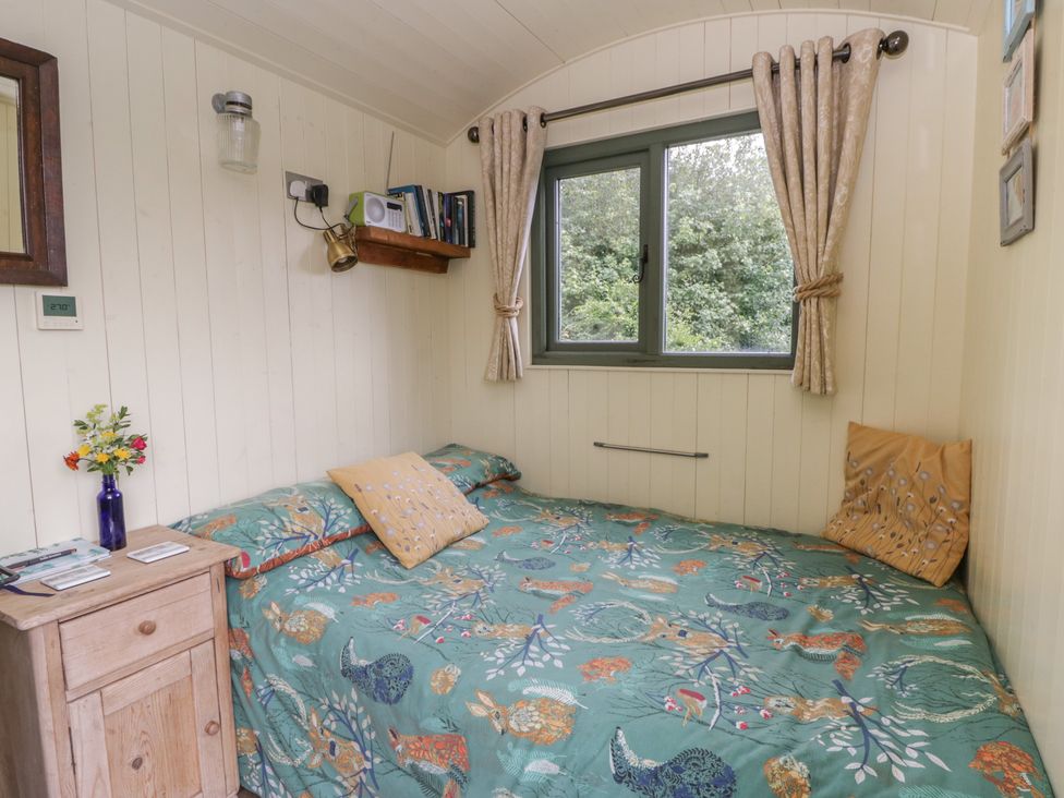 A bedroom with a bed and window at The Three Spaniels Shepherds Hut Cwrtnewydd near Llanybydder