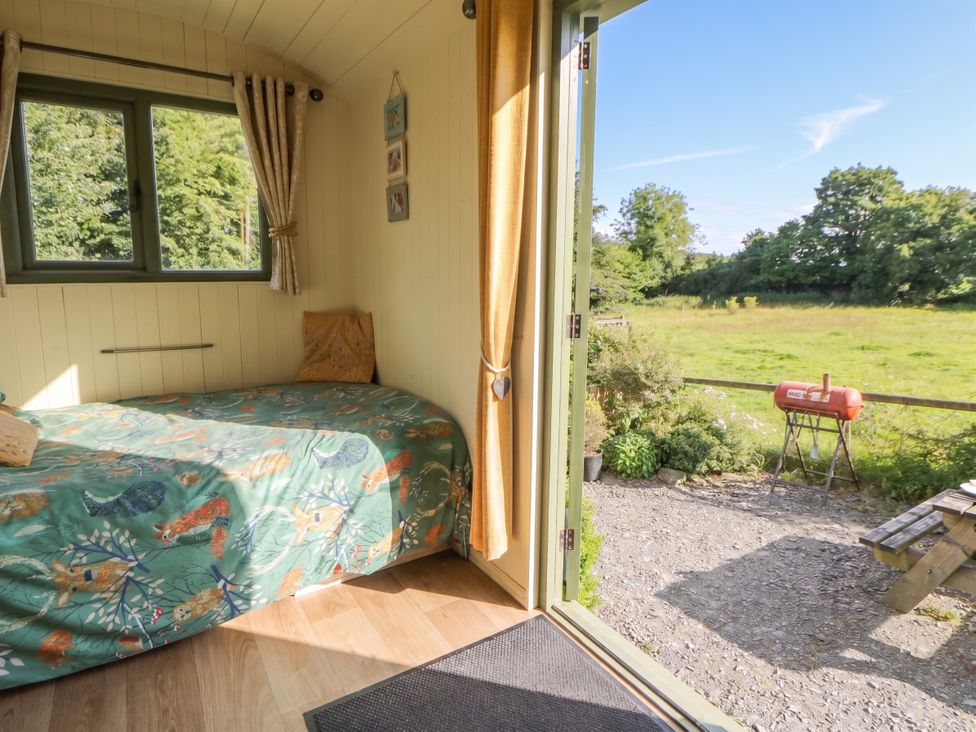 A hut with a bed and a view of the outdoor area at The Three Spaniels Shepherds Hut Cwrtnewydd near Llanybydder