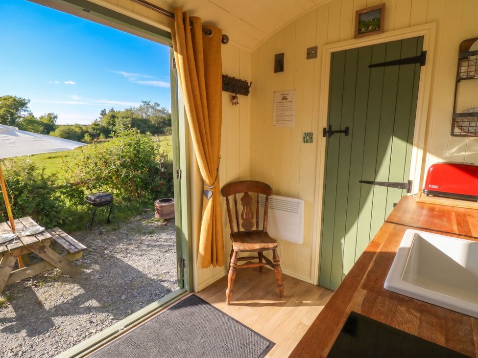 A kitchen with a chair and door leading outside at The Three Spaniels Shepherds Hut in Cwrtnewydd near Llanybydder