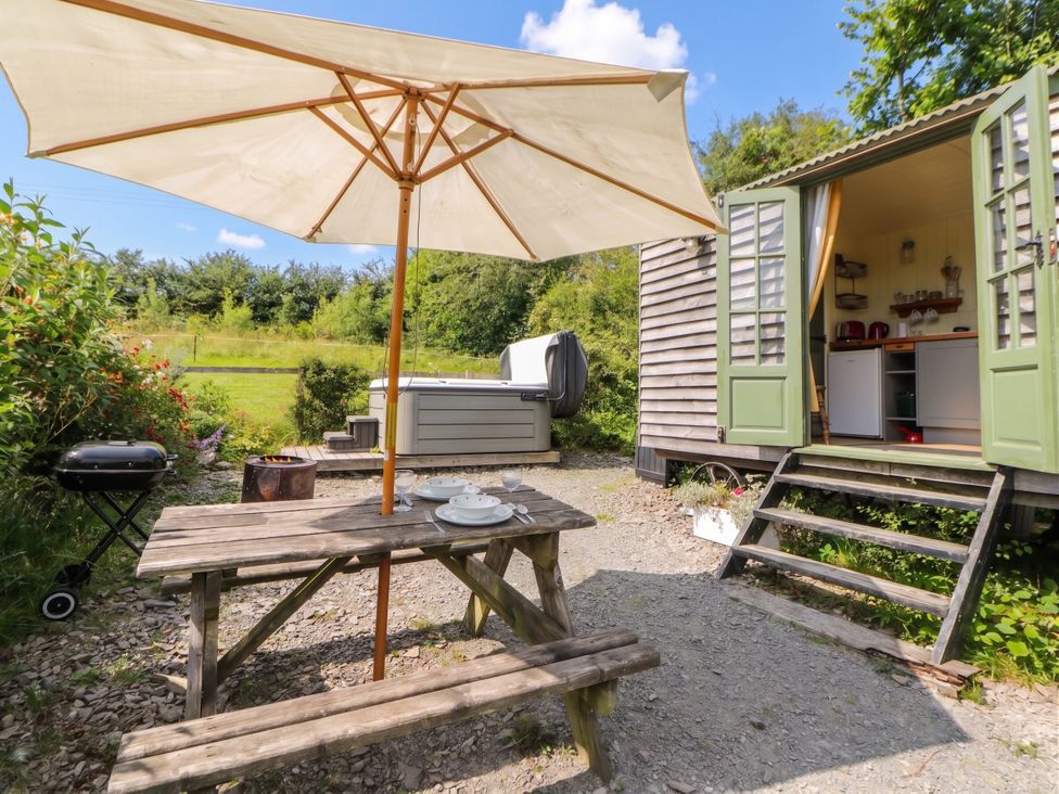 A garden with a table and parasol at The Three Spaniels Shepherds Hut Cwrtnewydd near Llanybydder