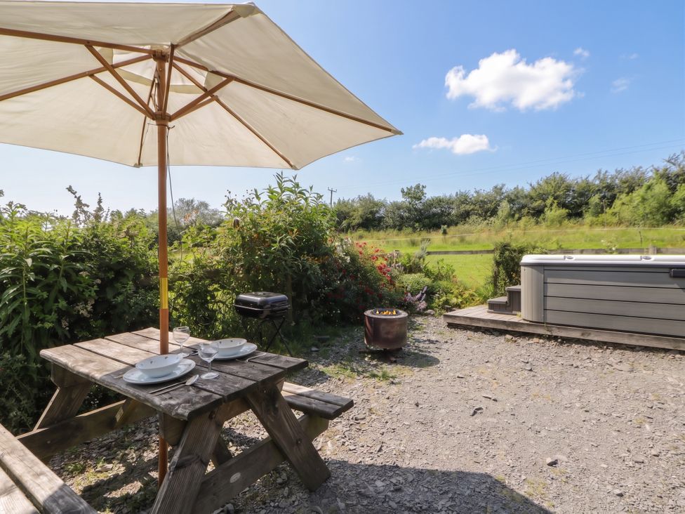 An outdoor dining area with a table and grill at The Three Spaniels Shepherds Hut Cwrtnewydd near Llanybydder