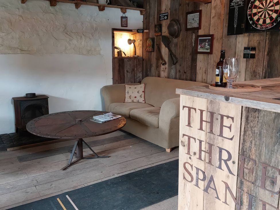 A snug with a sofa and a wood stove at The Three Spaniels Shepherds Hut in Lampeter