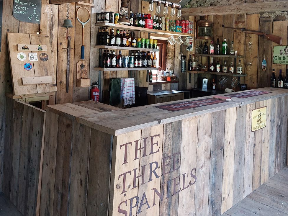A bar area with shelves of bottles and a counter at The Three Spaniels Shepherds Hut in Lampeter