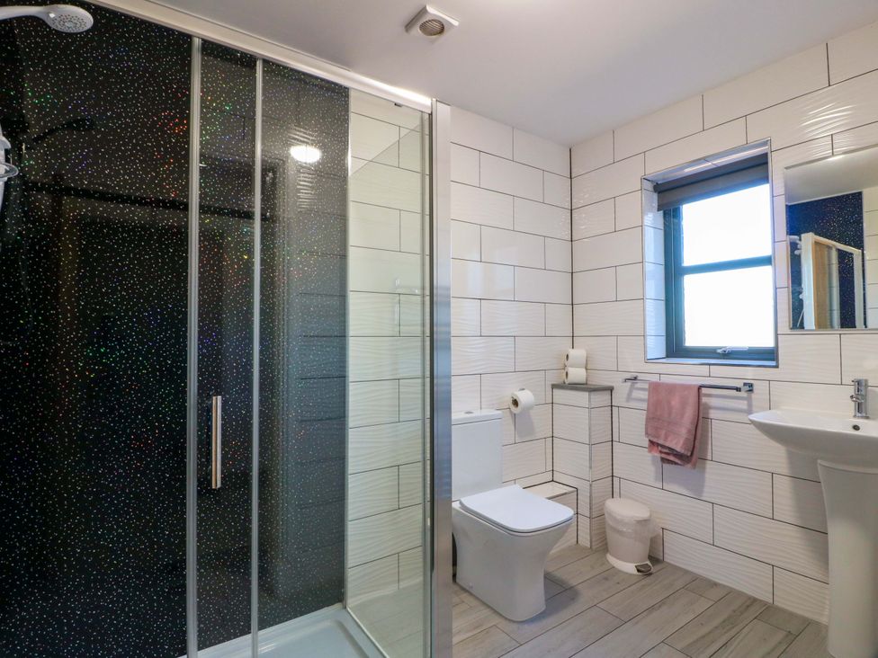 A bathroom with a shower, toilet, sink, and window at Ballaganlea in Alexandria