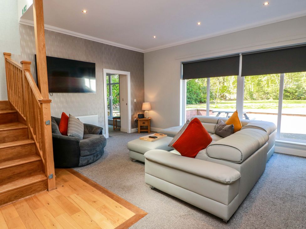 A living room with a sofa, armchair, and TV at Castle House Lodge in Glasgow