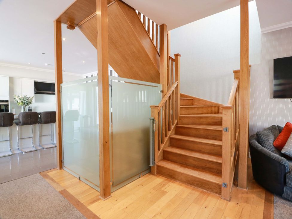 A living room with a staircase and glass partition at Castle House Lodge in Glasgow