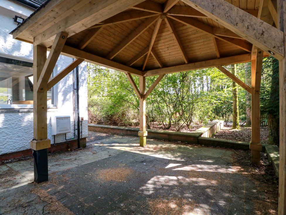 An outdoor area with a wooden gazebo and greenery at Castle House Lodge in Glasgow