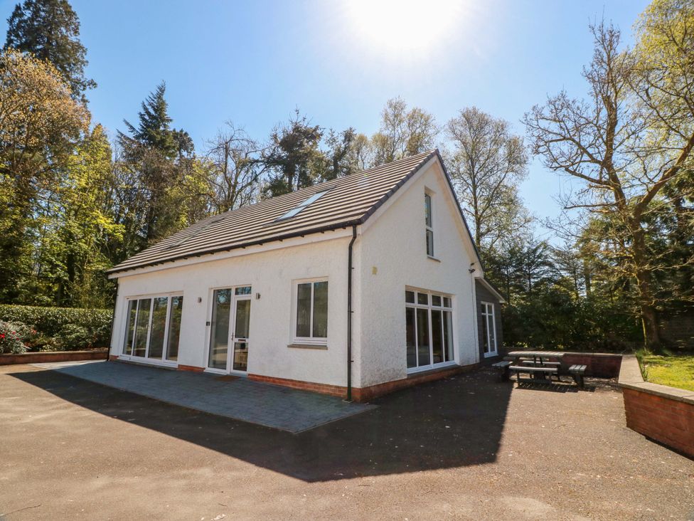 A house exterior with a patio area and trees at Castle House Lodge in Glasgow