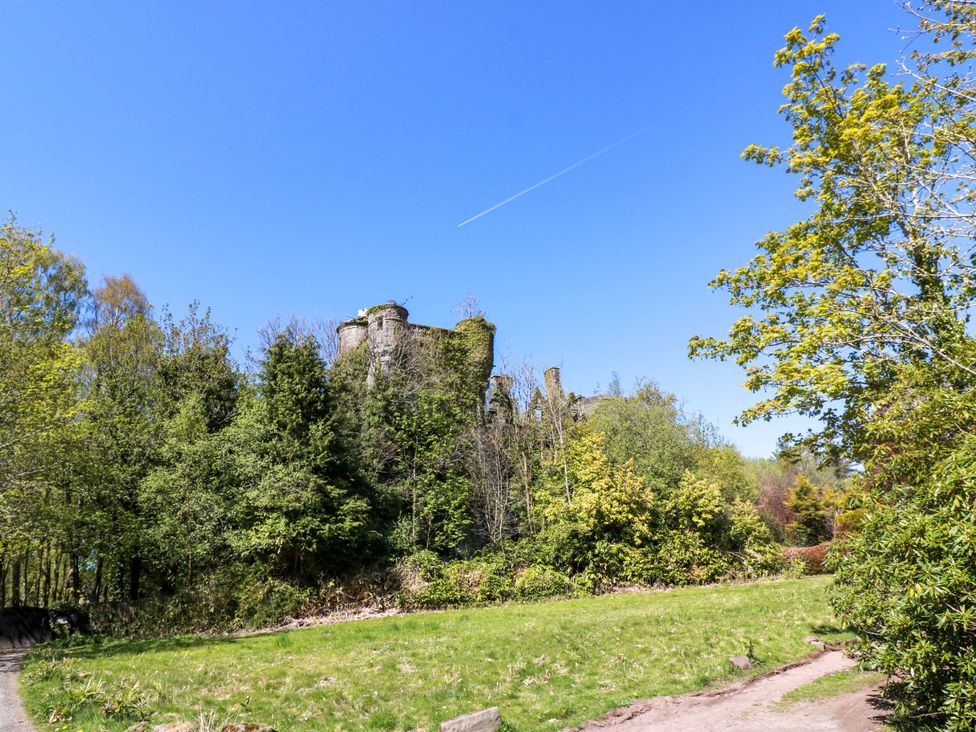Castle ruins surrounded by trees and grass with a pathway at Castle House Lodge in Glasgow