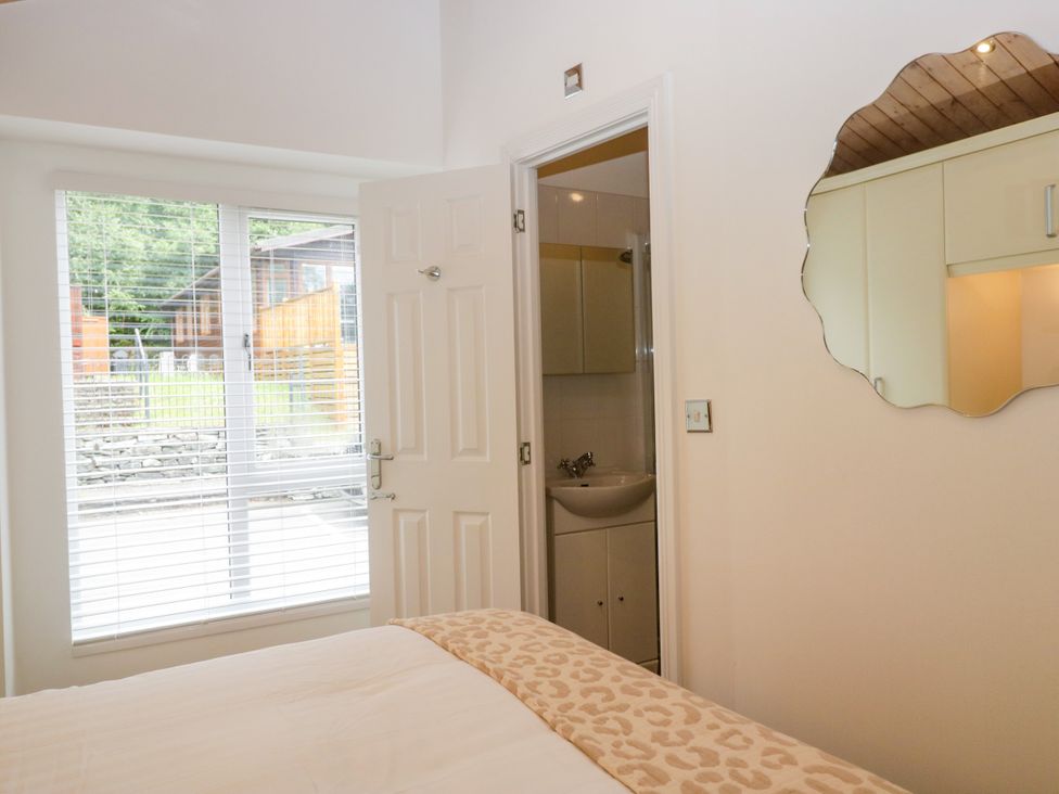 A bedroom with a bed and a door leading to an attached bathroom at Fox Red Retreat Troutbeck Bridge
