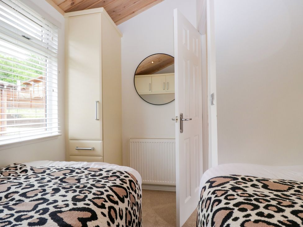 A bedroom with two beds and a wardrobe at Fox Red Retreat in Troutbeck Bridge