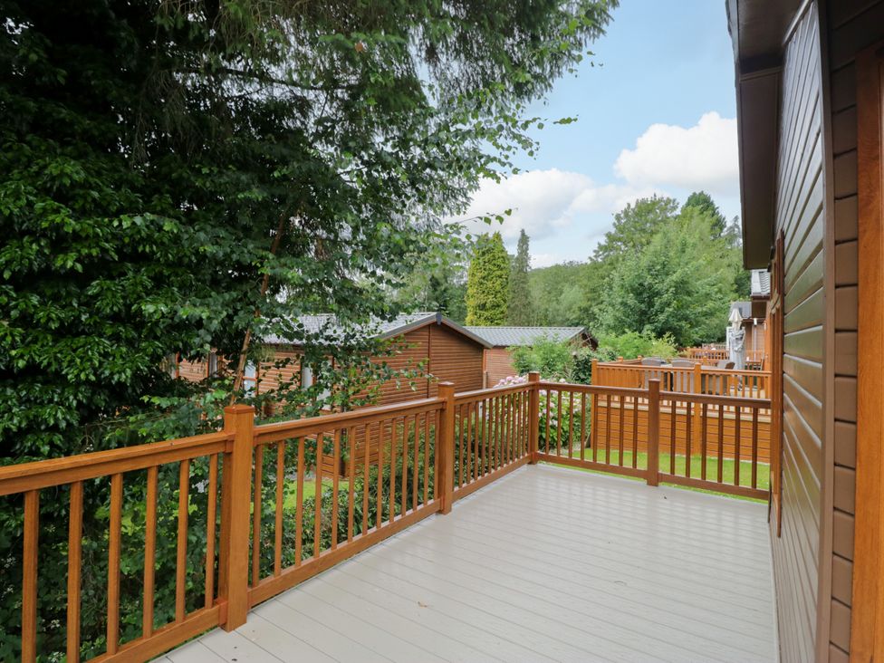 An outdoor deck with wooden railing and view of surrounding cabins at Fox Red Retreat Troutbeck Bridge