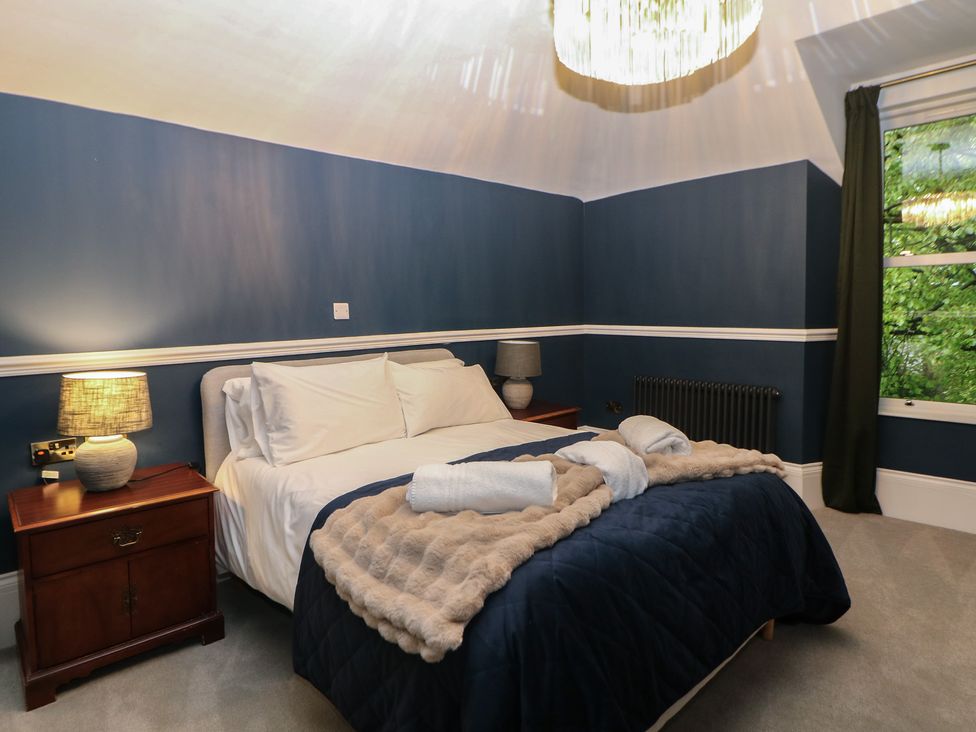 A bedroom with a bed, nightstand, and window at The Loft Suite in Buxton