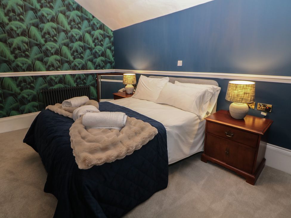 A bedroom with a bed and nightstand at The Loft Suite in Buxton