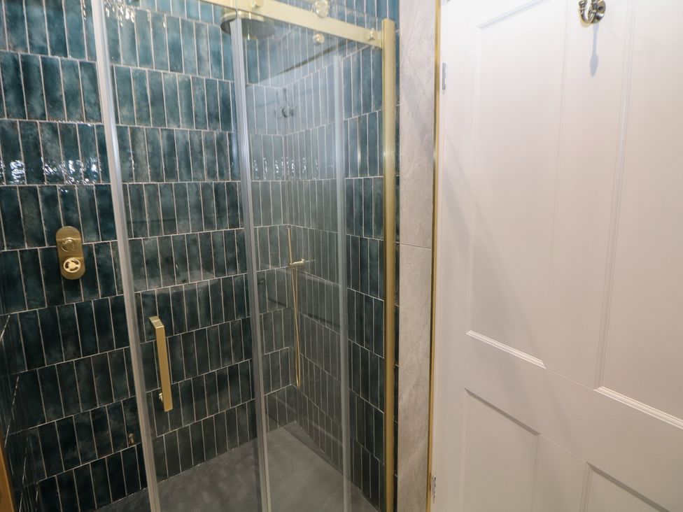 A shower with glass door and tiled walls at The Loft Suite in Buxton