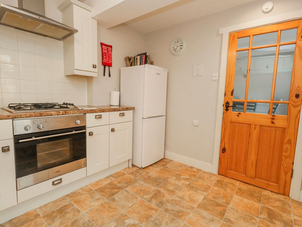 A kitchen with an oven, gas stove, refrigerator and door at 12 West Street Weymouth