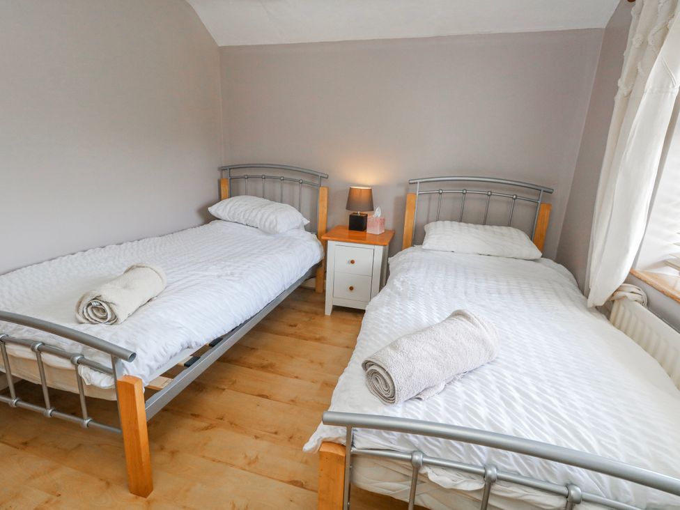 A bedroom with two beds and a bedside table at 12 West Street in Weymouth